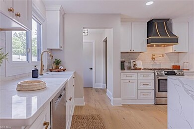Kitchen with custom exhaust hood, white cabinetry,
