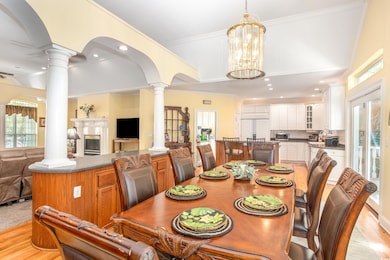 Dining space with decorative columns, healthy amount of natural light, light wood finished floors, crown molding, and recessed lighting