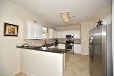 Kitchen featuring stainless steel appliances, a peninsula, tasteful backsplash, white cabinets, and dark countertops