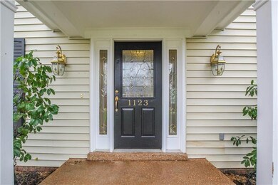 The covered front porch leads to the front door, with its beautiful leaded glass front and side lights