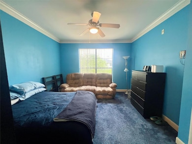 Bedroom featuring baseboards, dark carpet, crown 