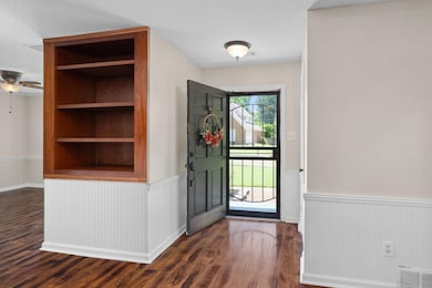 Foyer entrance featuring a wainscoted wall, dark wood-style flooring, a ceiling fan, and a textured ceiling