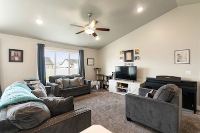 Carpeted living area featuring vaulted ceiling, ceiling fan, and recessed lighting