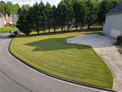 View of green lawn featuring an attached garage, a residential view, and driveway