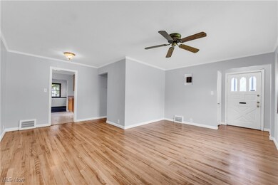 Unfurnished living room with ornamental molding, light wood-type flooring, and ceiling fan