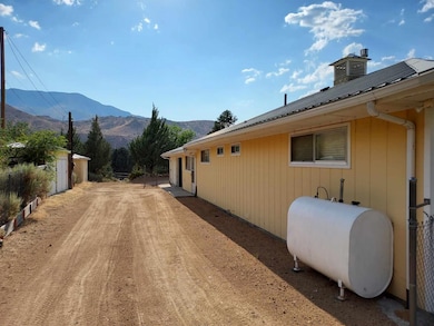 View of side of property with heating fuel, a mountain view, and a metal roof