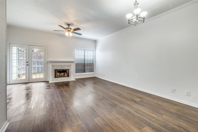 Unfurnished living room with ornamental molding, a premium fireplace, dark wood-style flooring, ceiling fan, and a chandelier