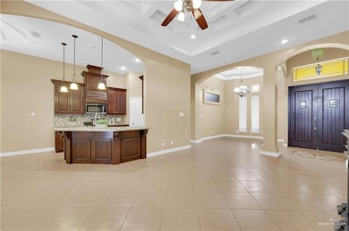 Kitchen featuring arched walkways, tasteful backsplash, open floor plan, light tile patterned flooring, and a kitchen bar