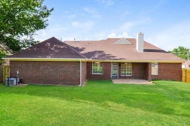 Rear view of property with a patio area, a chimney, brick siding, and a shingled roof