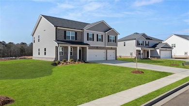 View of front of house featuring a garage, driveway, brick siding, and a front yard