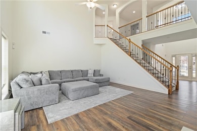 Living area featuring a towering ceiling, stairway, dark wood-type flooring, a ceiling fan, and recessed lighting