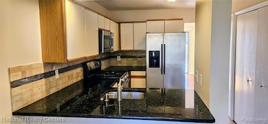 Kitchen with appliances with stainless steel finishes, dark stone countertops, and decorative backsplash