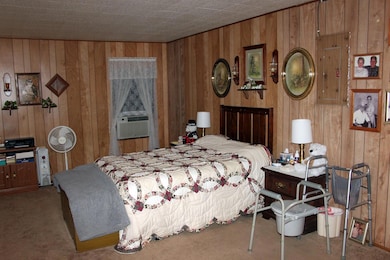 Bedroom featuring wood walls, carpet floors, and cooling unit