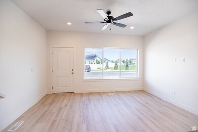 Family room with large windows, laminate flooring and ceiling fan.