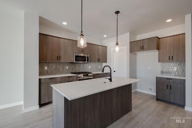 Kitchen featuring decorative light fixtures, decorative backsplash, stainless steel appliances, modern cabinets, and light stone counters