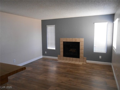 Unfurnished living room featuring a textured ceiling, wood finished floors, healthy amount of natural light, and a tile fireplace