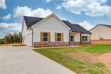 View of front of house with stone siding, roof with shingles, and a front yard