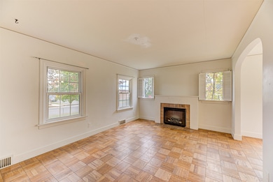Unfurnished living room featuring arched walkways and a brick fireplace