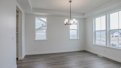 Unfurnished dining area featuring a chandelier, wood finished floors, and a raised ceiling