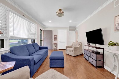 Living room with wood finished floors, recessed lighting, and ornamental molding
