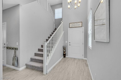 Entryway featuring a high ceiling, light wood-style floors, stairs, and a chandelier
