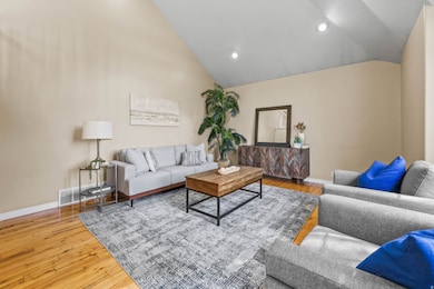 Living area with recessed lighting, light wood finished floors, and high vaulted ceiling