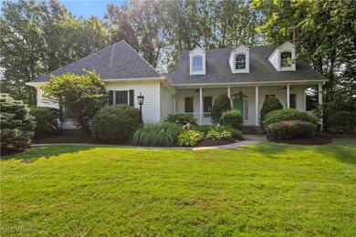 New england style home featuring a shingled roof, a front yard, and a porch