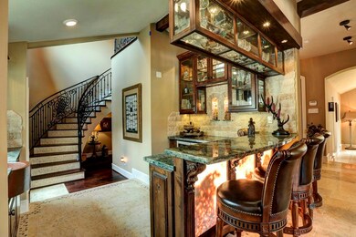 The wet bar, which is complete with plenty of custom glass cabinetry, exotic granite, stone wall, wine chiller, and beverage center makes the perfect place to entertain.