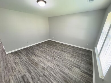 Spare room featuring baseboards and dark wood-type flooring