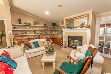 Carpeted living room featuring a fireplace, lofted ceiling, and crown molding