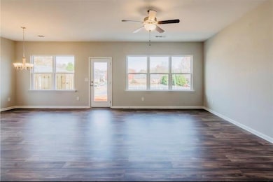Unfurnished room featuring dark wood finished floors, a chandelier, and a ceiling fan