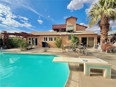 Back of house with a pergola, an outdoor pool, and