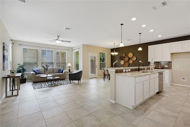 Kitchen with white cabinetry, open floor plan, light stone counters, decorative light fixtures, and recessed lighting