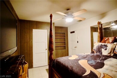 Primary bedroom has tile flooring and ceiling fan