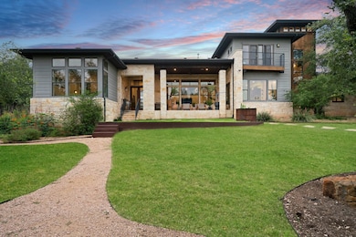 Back of property at dusk featuring stone siding, a yard, and a patio