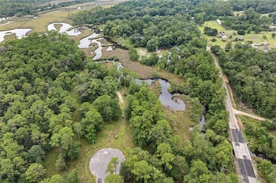 Aerial overview of property's location featuring a nearby body of water and a heavily wooded area