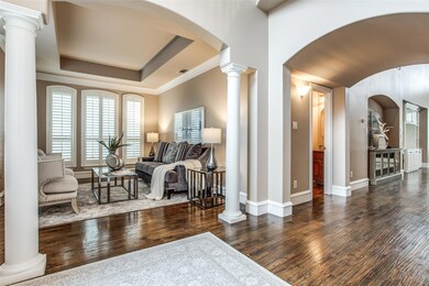 Foyer entrance featuring dark haod-scraped hardwood flooring, crown molding, ornate columns, and a tray ceiling