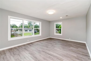 Unfurnished room featuring healthy amount of natural light, baseboards, and wood finished floors
