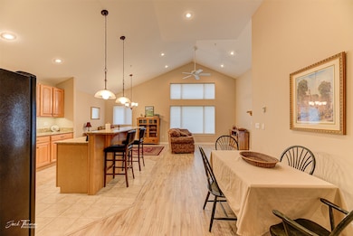Dining space featuring ceiling fan, high vaulted ceiling, and light hardwood / wood-style floors
