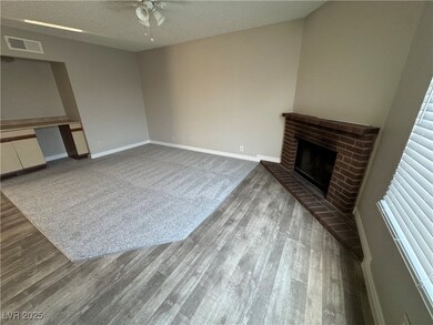 Unfurnished living room with a textured ceiling, a fireplace, wood finished floors, and built in study area