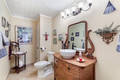 This charming bathroom features a vintage-style wooden vanity with a modern vessel sink and elegant fixtures. The space is accented with tasteful wall decor, a decorative mirror, and soft lighting, creating a cozy and inviting atmosphere.