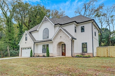 Modern farmhouse with board and batten siding, a shingled roof, and driveway