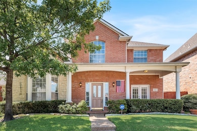 Traditional-style home featuring covered porch, brick siding, and a front yard