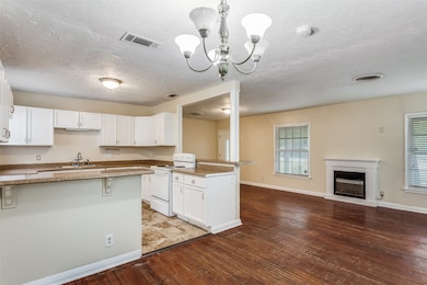 Kitchen featuring white electric range, white cabinetry, a peninsula, a kitchen breakfast bar, and open floor plan