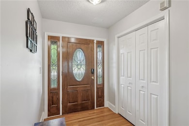Foyer entrance featuring baseboards, a textured ce