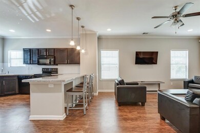 Kitchen with black appliances, open floor plan, a breakfast bar area, dark brown cabinetry, and crown molding