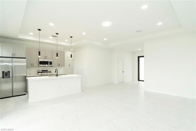 Kitchen featuring a tray ceiling, appliances with stainless steel finishes, an island with sink, recessed lighting, and open floor plan