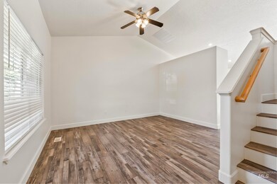 Spare room with stairway, plenty of natural light, wood finished floors, lofted ceiling, and ceiling fan
