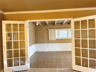 Empty room with crown molding, beam ceiling, a wai