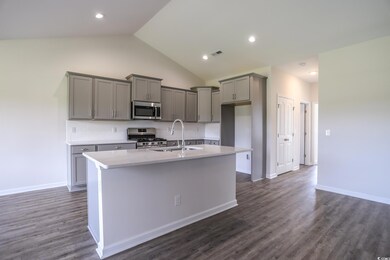 Kitchen featuring vaulted ceiling, an island with 